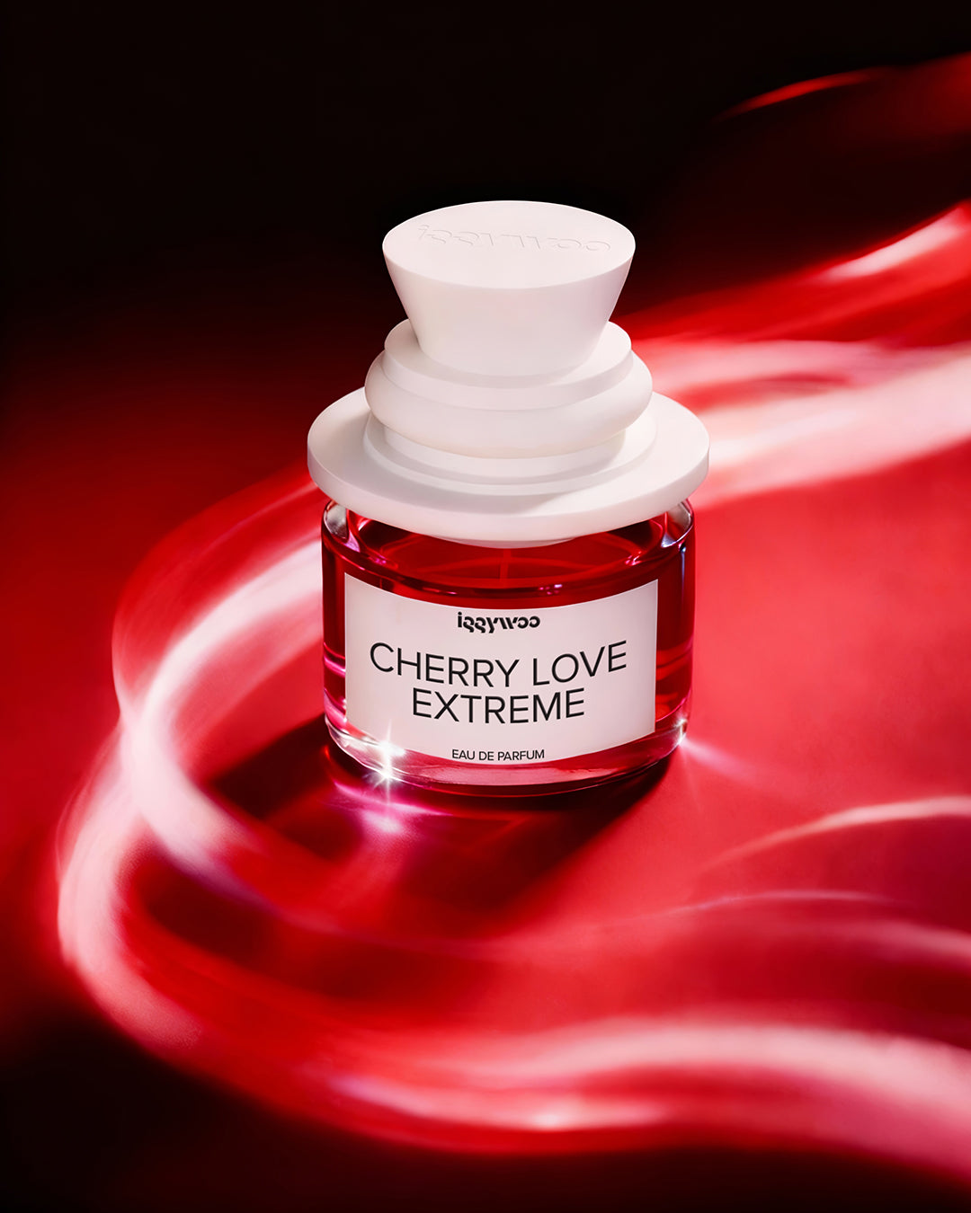 A small glass perfume bottle labeled 'lggywoo CHERRY LOVE EXTREME' with a white cap, filled with red liquid, set against a dark red and black background with glowing red light streaks.