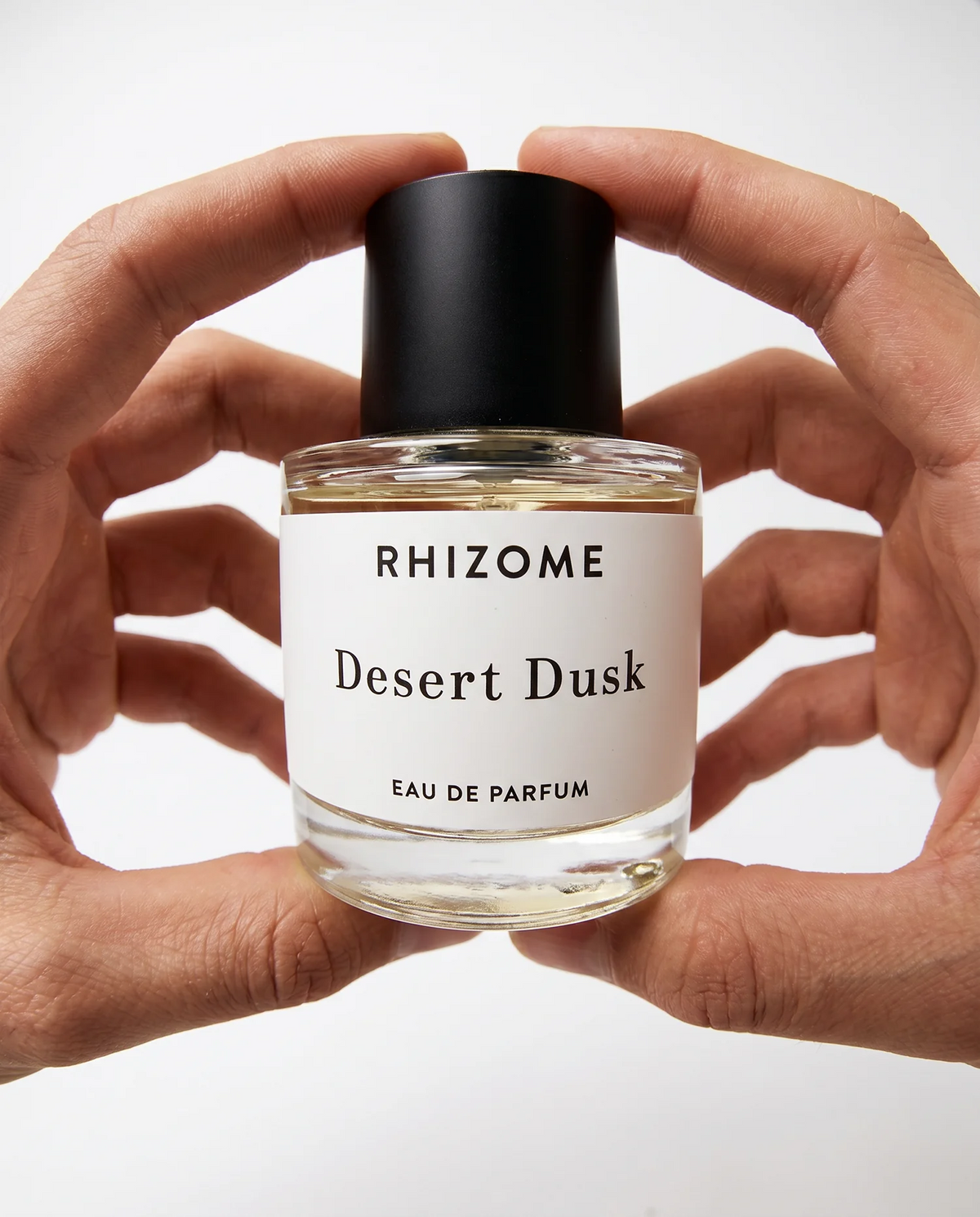 Rhizome Desert Dusk eau de parfum held in hands against a neutral background