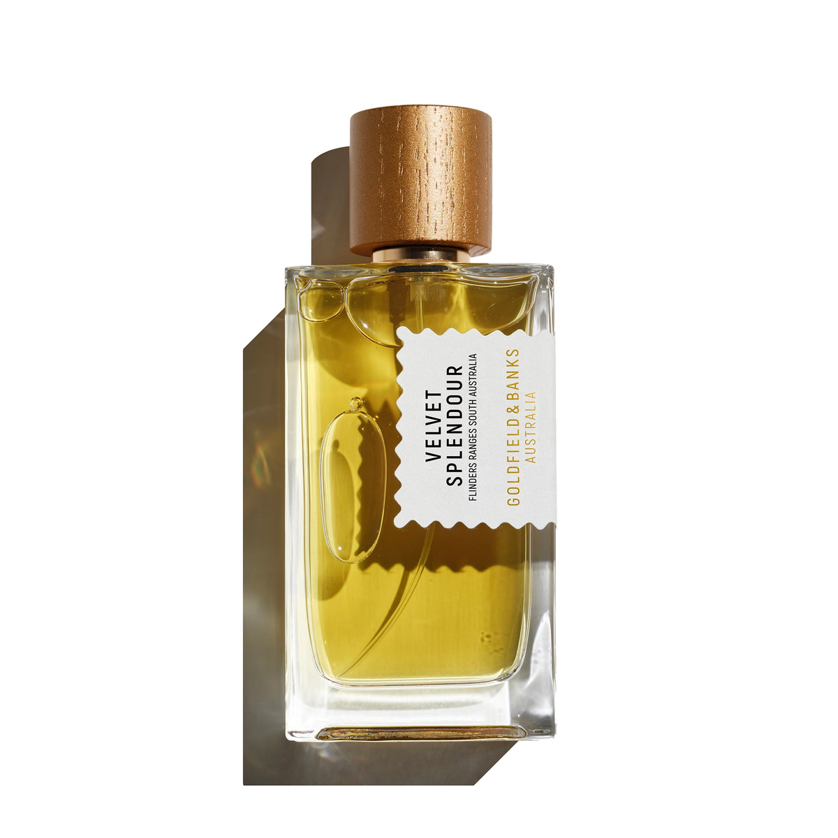 A rectangular glass perfume bottle filled with golden yellow liquid, featuring a metallic gold cap and a white label that reads 'VELVET SPLENDOUR' and 'GOLDEN BANKS AUSTRALIA'. The bottle is photographed on a clean white background with a soft shadow cast to the left.