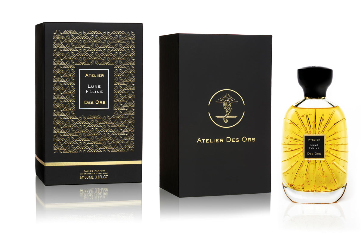 Atelier Des Ors Lune Feline Eau de Parfum shown with its black patterned outer box, black inner box, and a faceted clear glass bottle filled with golden-yellow liquid.